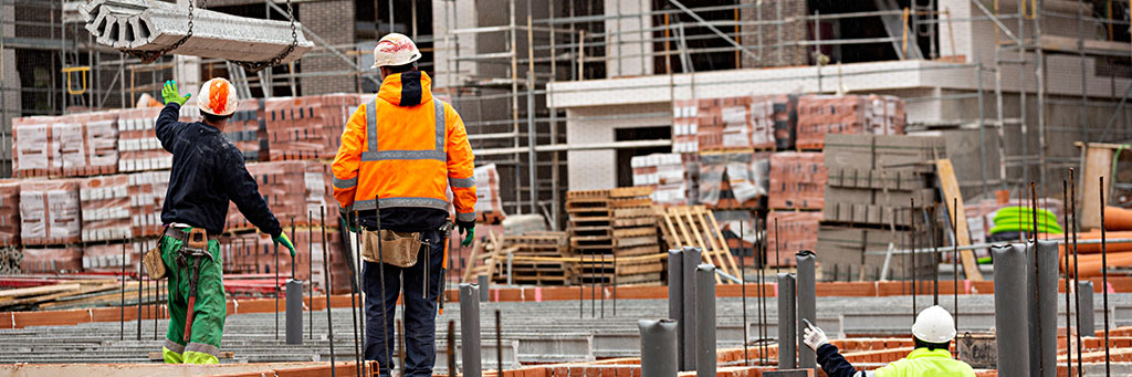 Building Site Accident Compensation Claims - Picture of a building site with people wearing hard hats and high viability clothing.